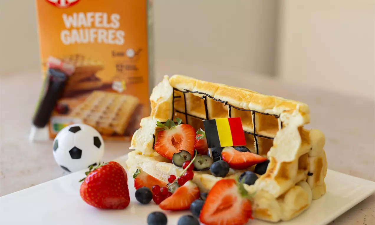Gaufres dorées et moelleuses formant une cage de football, décorées de fruits rouges, myrtilles et un petit drapeau belge sur une assiette blanche